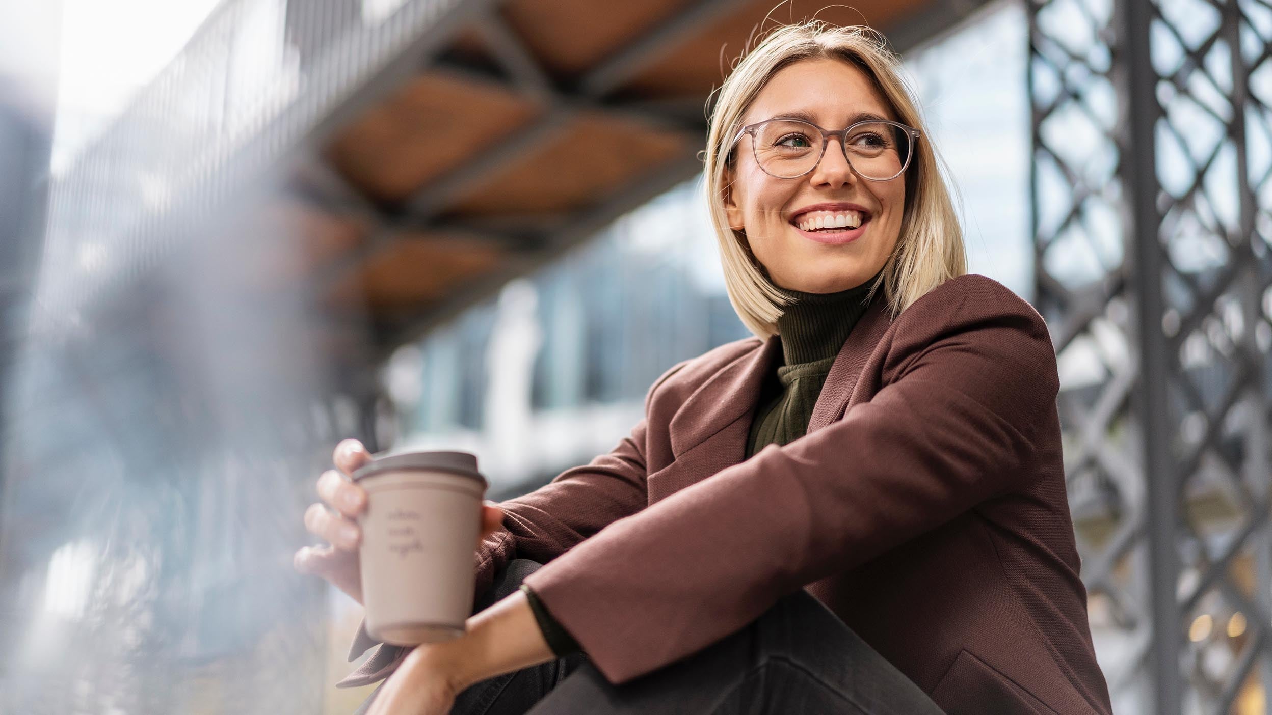 Een jongedame die geniet van een kopje koffie, staat symbool voor de manier waarop innovatie floreert op onverwachte plekken, inclusief enkele van de onderliggende beleggingen van Invesco QQQ ETF.