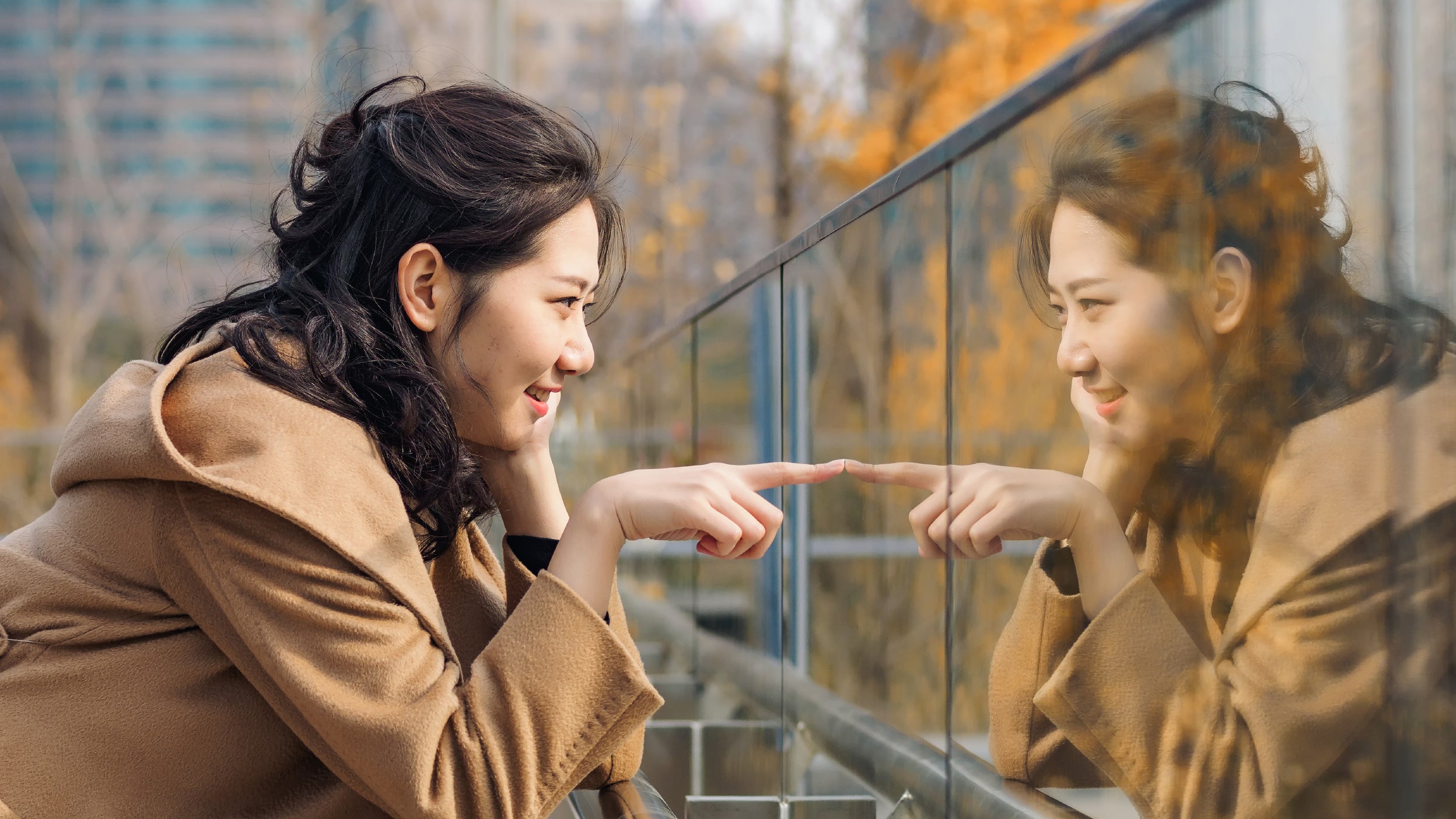 beautiful chinese girl looking at her mirror image in glass.