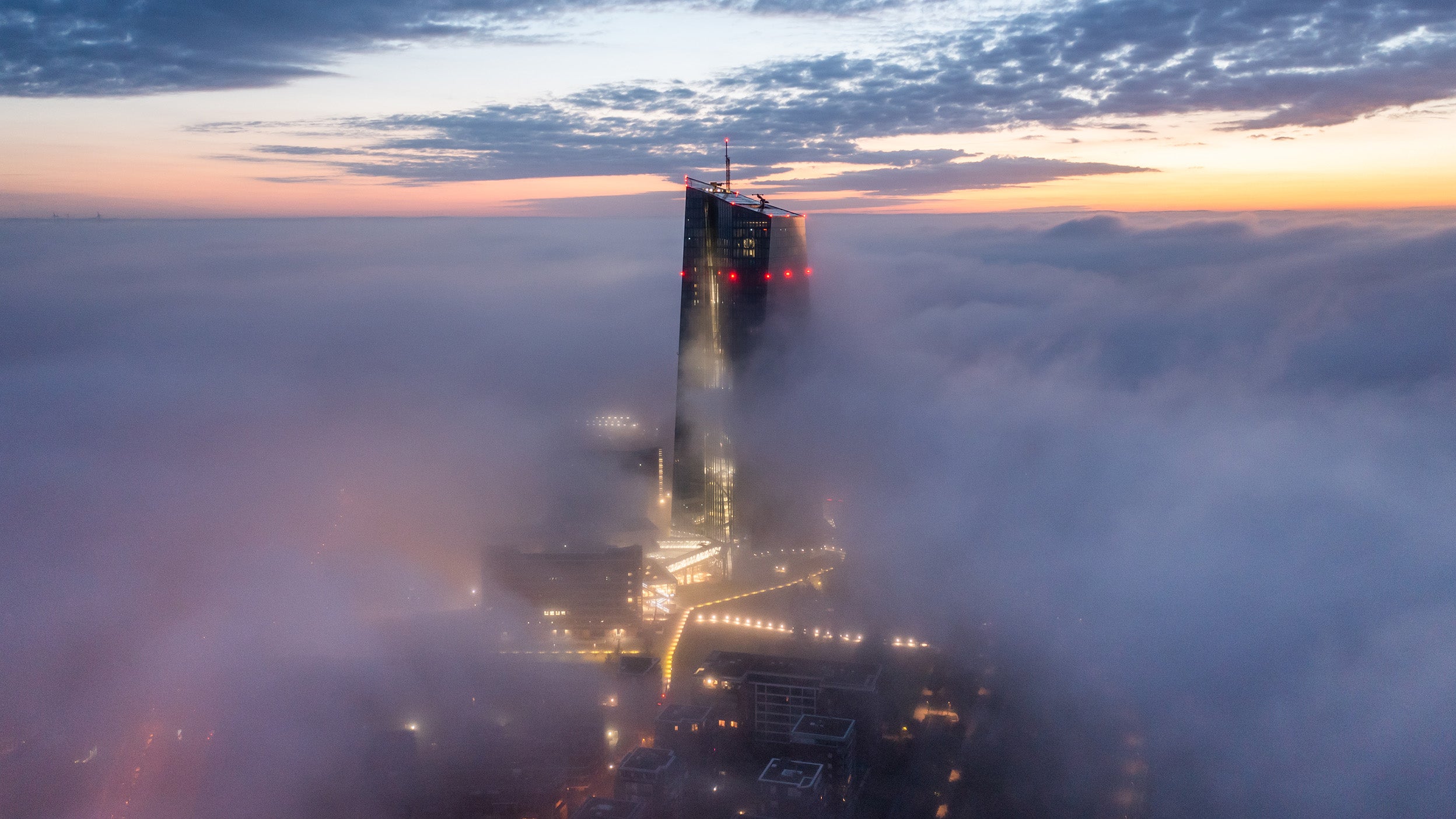 A sunrise in Frankfurt. The European Central Bank building sticking out of the fog while the sun is rising.