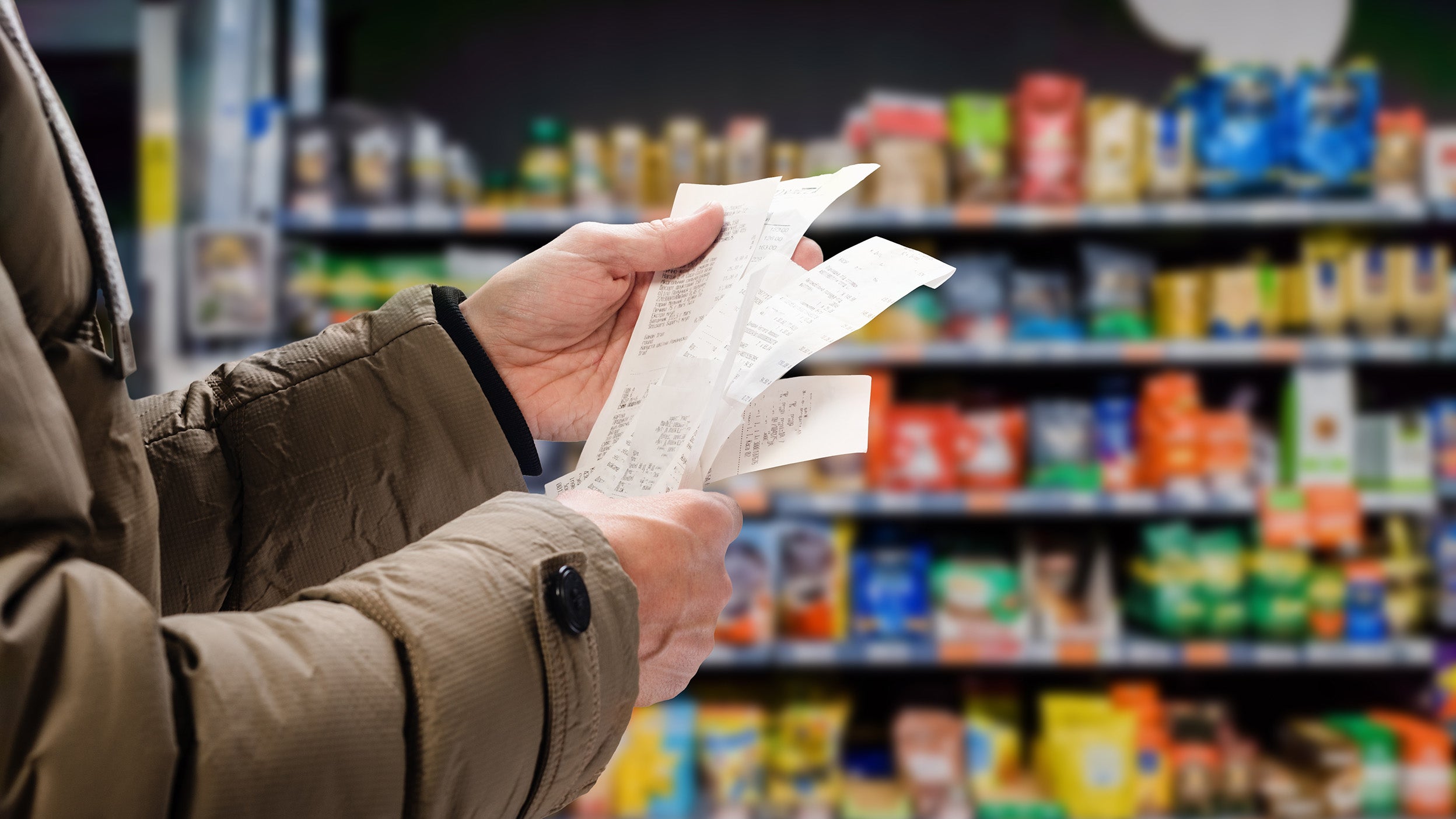 Minded man viewing receipts in supermarket and tracking prices 