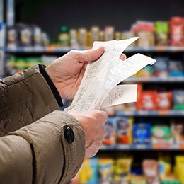 Minded man viewing receipts in supermarket and tracking prices 