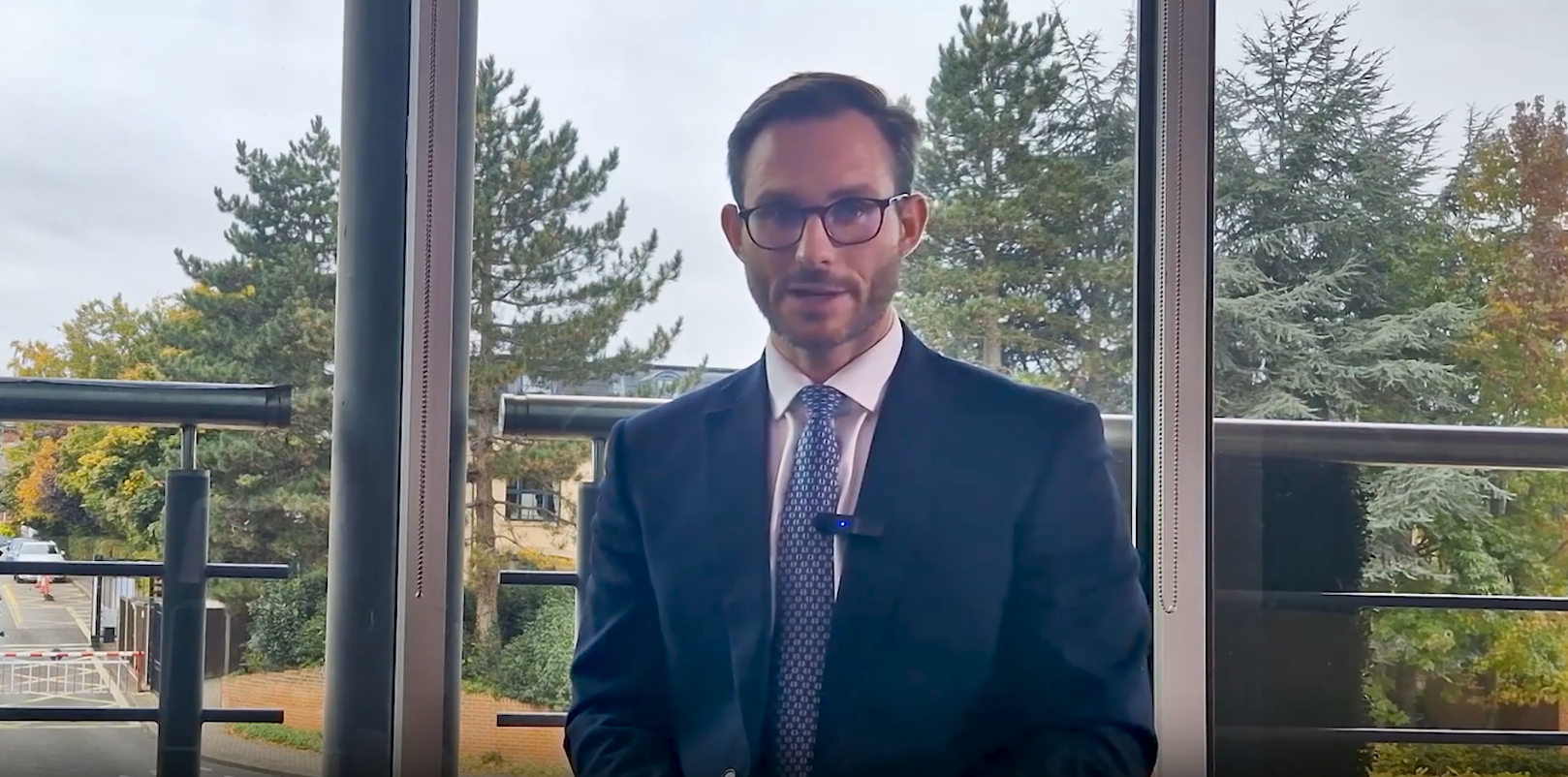 Joe Dowling speaking directly to the camera in a professional office setting.