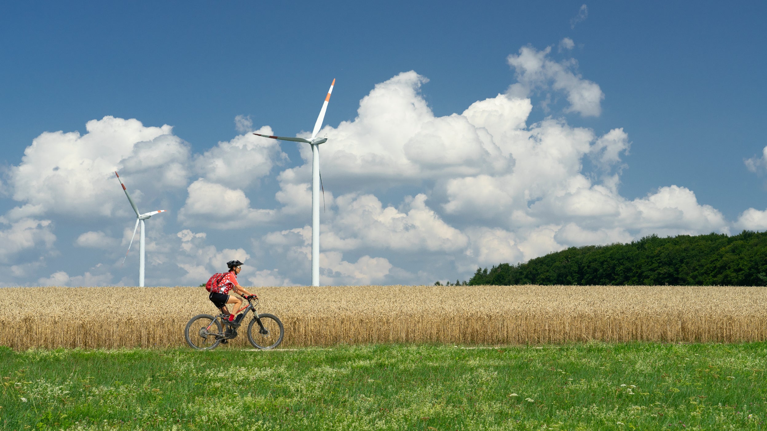 Woman riding a bike in filed with wind turbines in the background