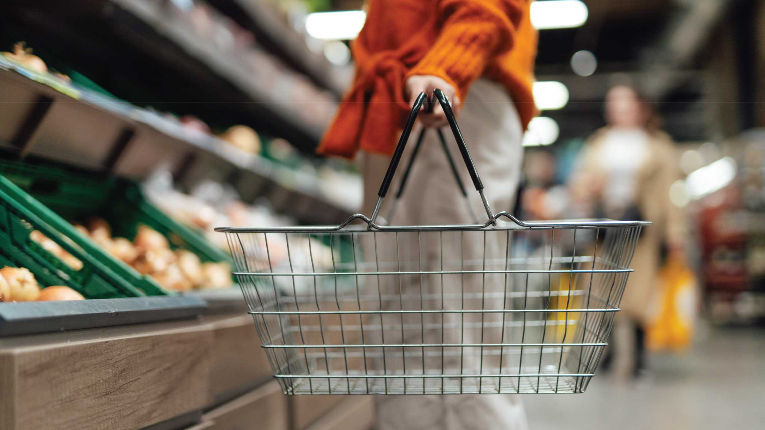 Lower section of young woman standing next to product aisle and choosing vegetables in the store. Young Asian woman doing grocery shopping in supermarket.