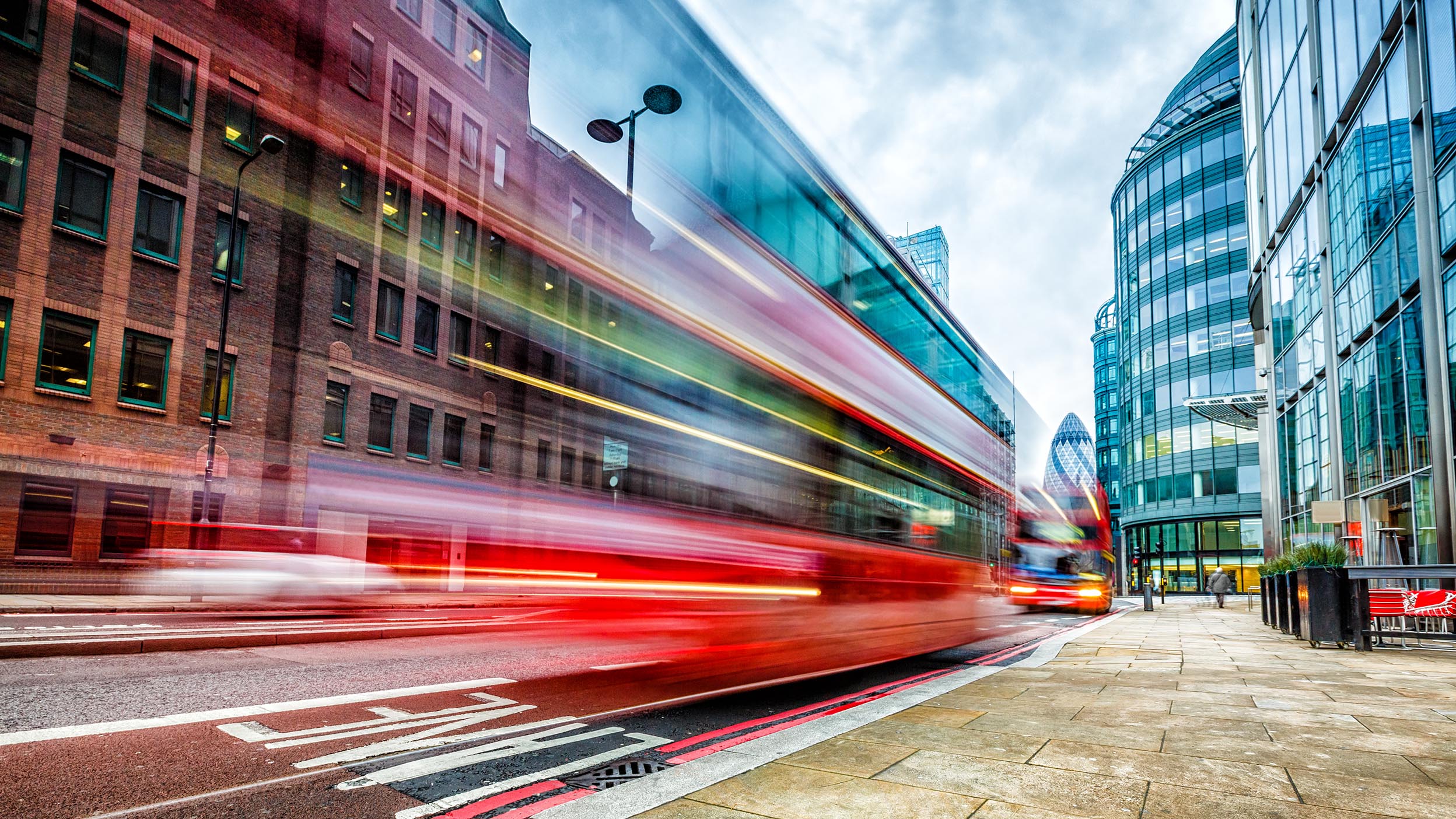 A red double-decker bus driving along Bishopsgate in London.