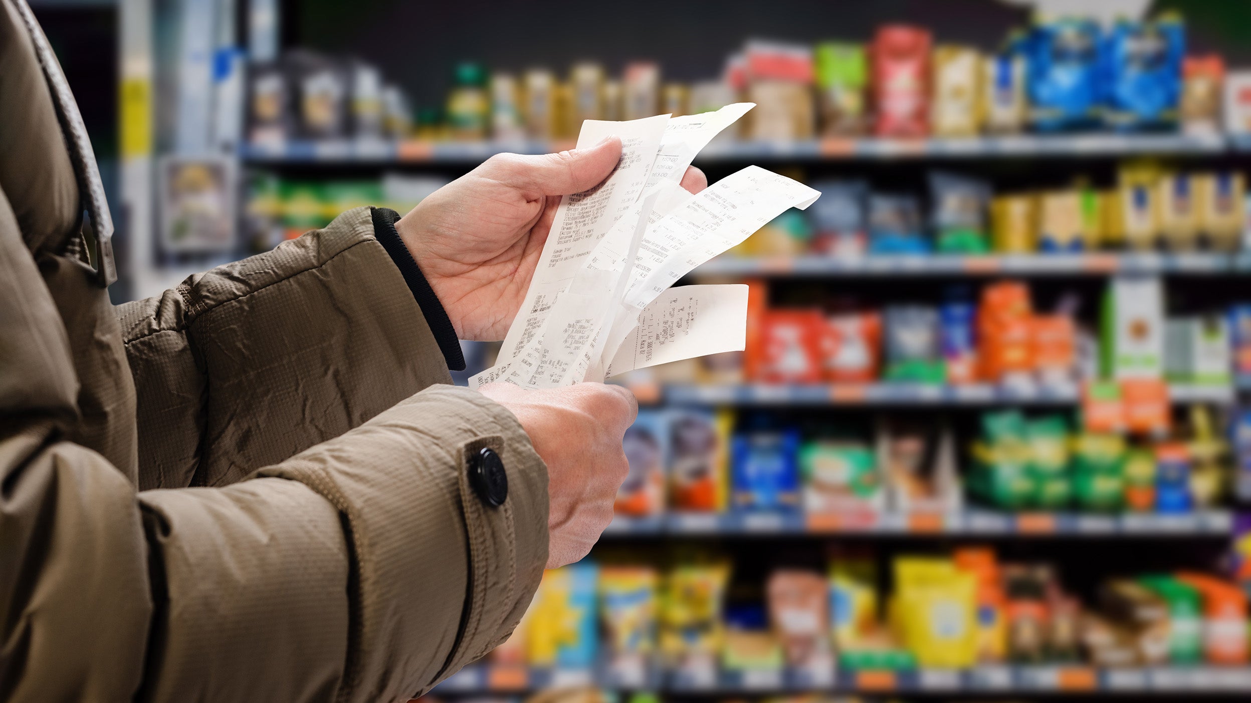 Man viewing receipts in supermarket and tracking prices.