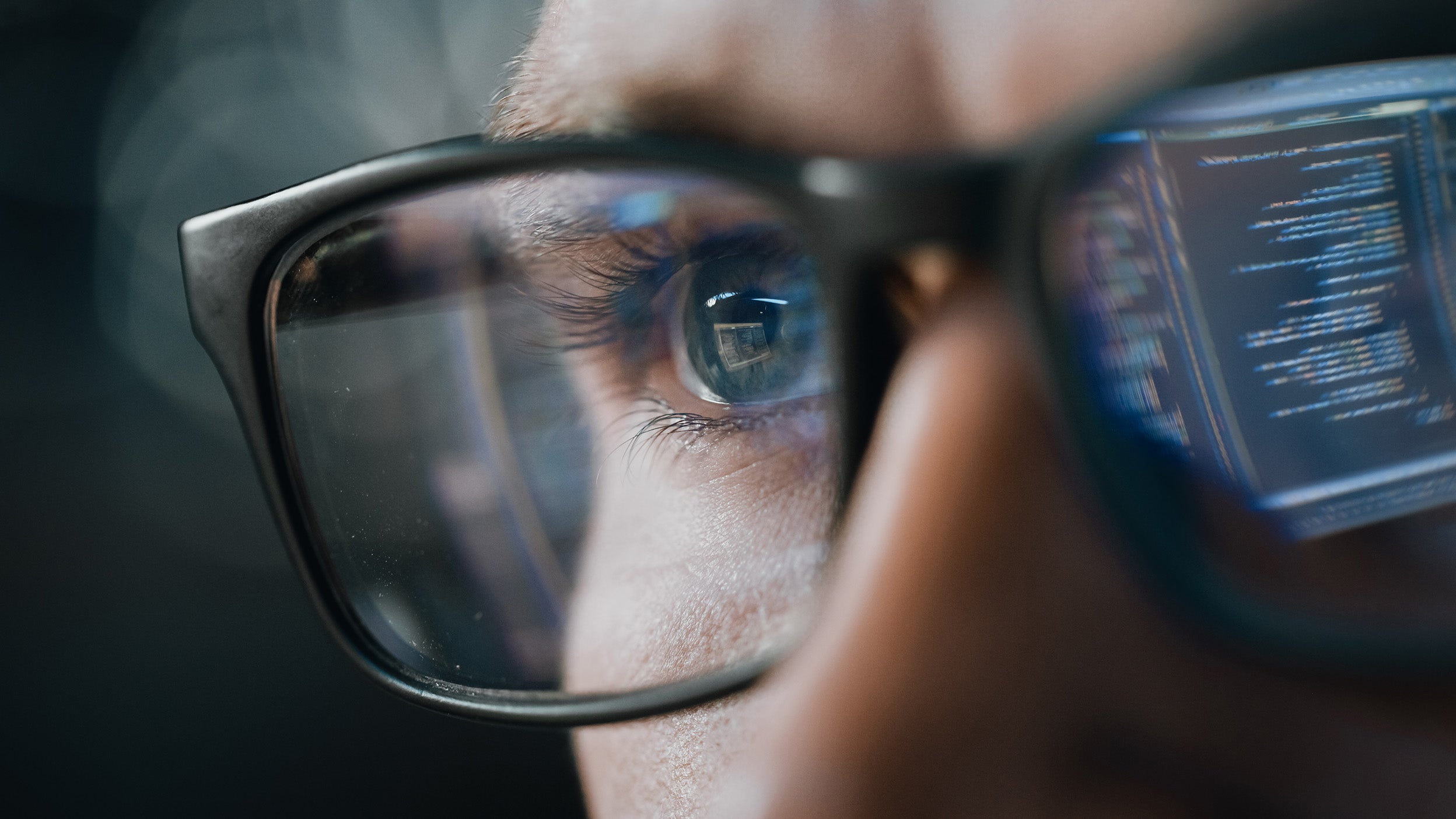 A reflection of a computer screen with coding language in a person’s eyeglasses.