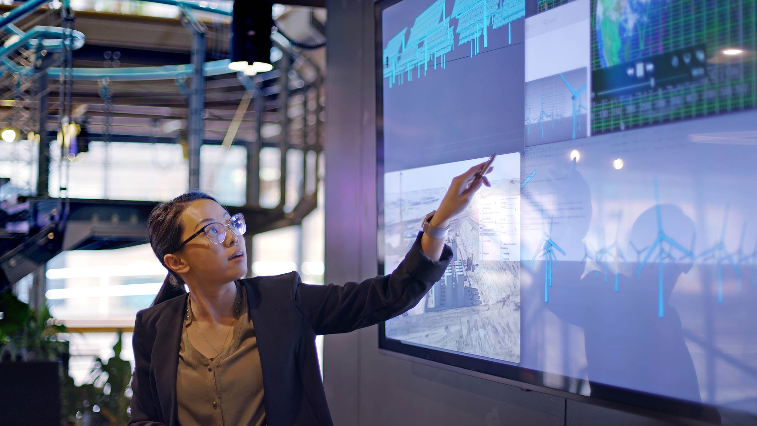 Woman conducting a seminar on tech with the aid of a large screen.