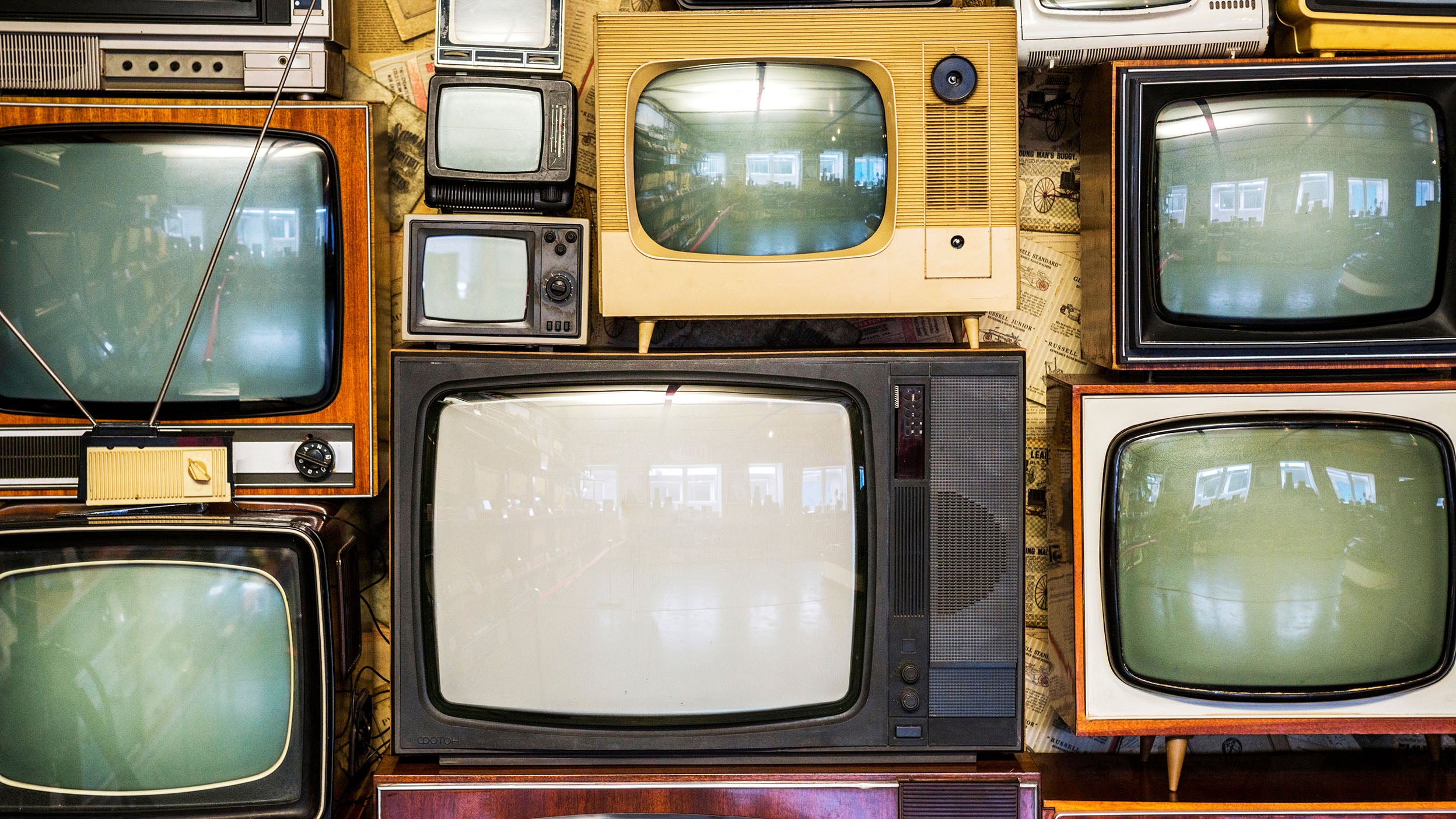 A wall of old vintage tube televisions stacked up.