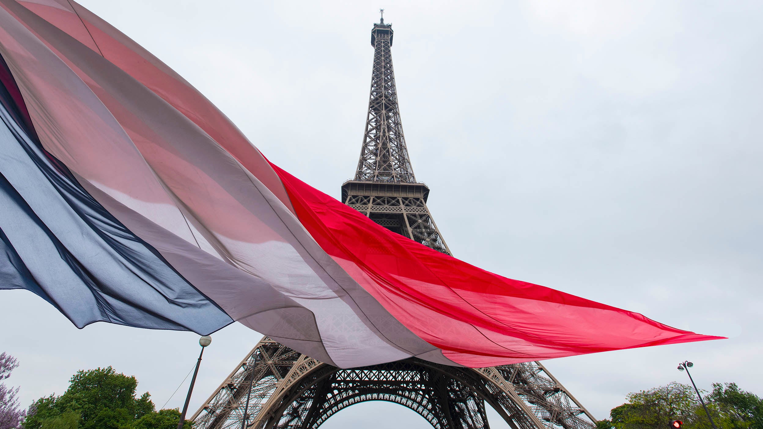 La tour Eiffel avec le drapeau français au premier plan.
