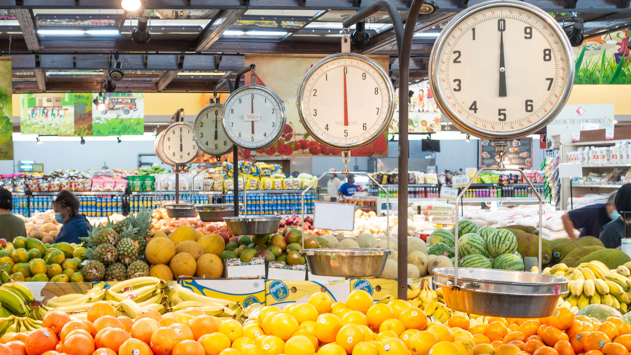 Balances suspendues dans la section des fruits d’un supermarché pour que les clients pèsent leurs fruits et légumes.