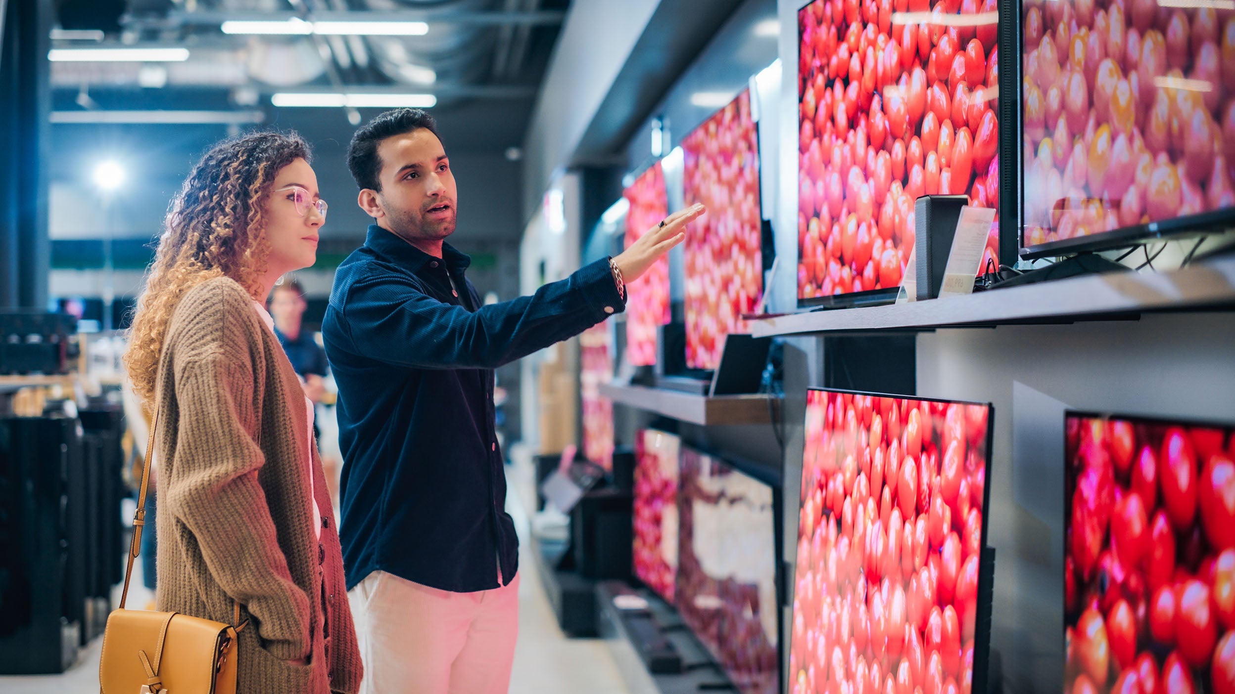 Customers shop for televisions.