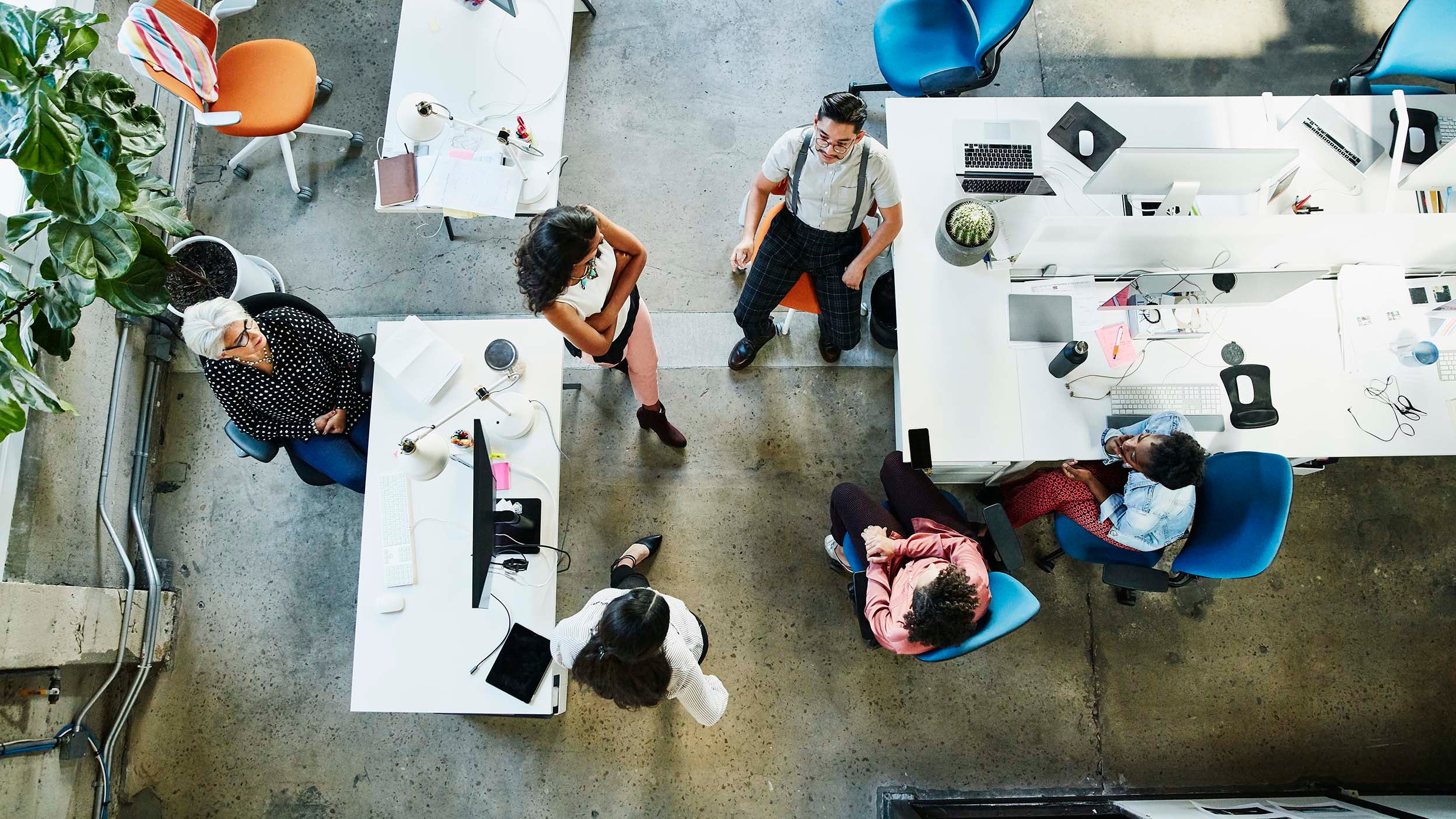 Overhead view of design team having project meeting in an office of a company that could be a future holding of Invesco QQQ ETF.