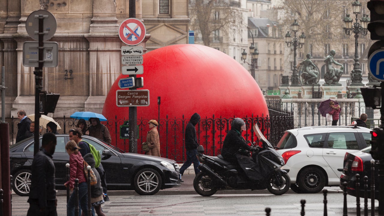 Pedestrians walk past American artist Kurt Perschke's installation 'RedBall Project' at Hotel De Ville on April 19, 2013 in Paris, France