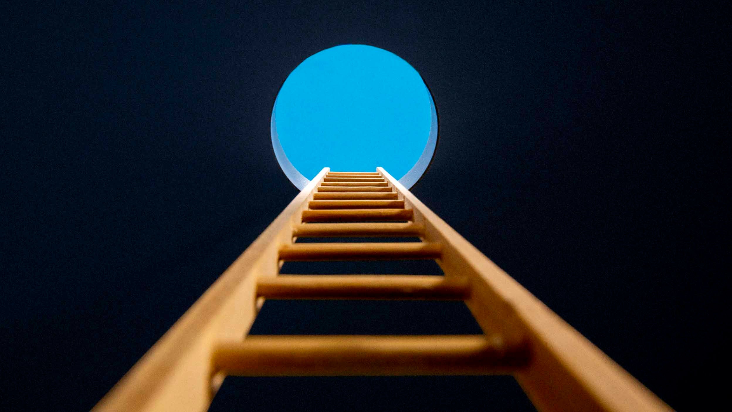 Point of view, looking up ladder sticking through hole in ceiling revealing blue sky