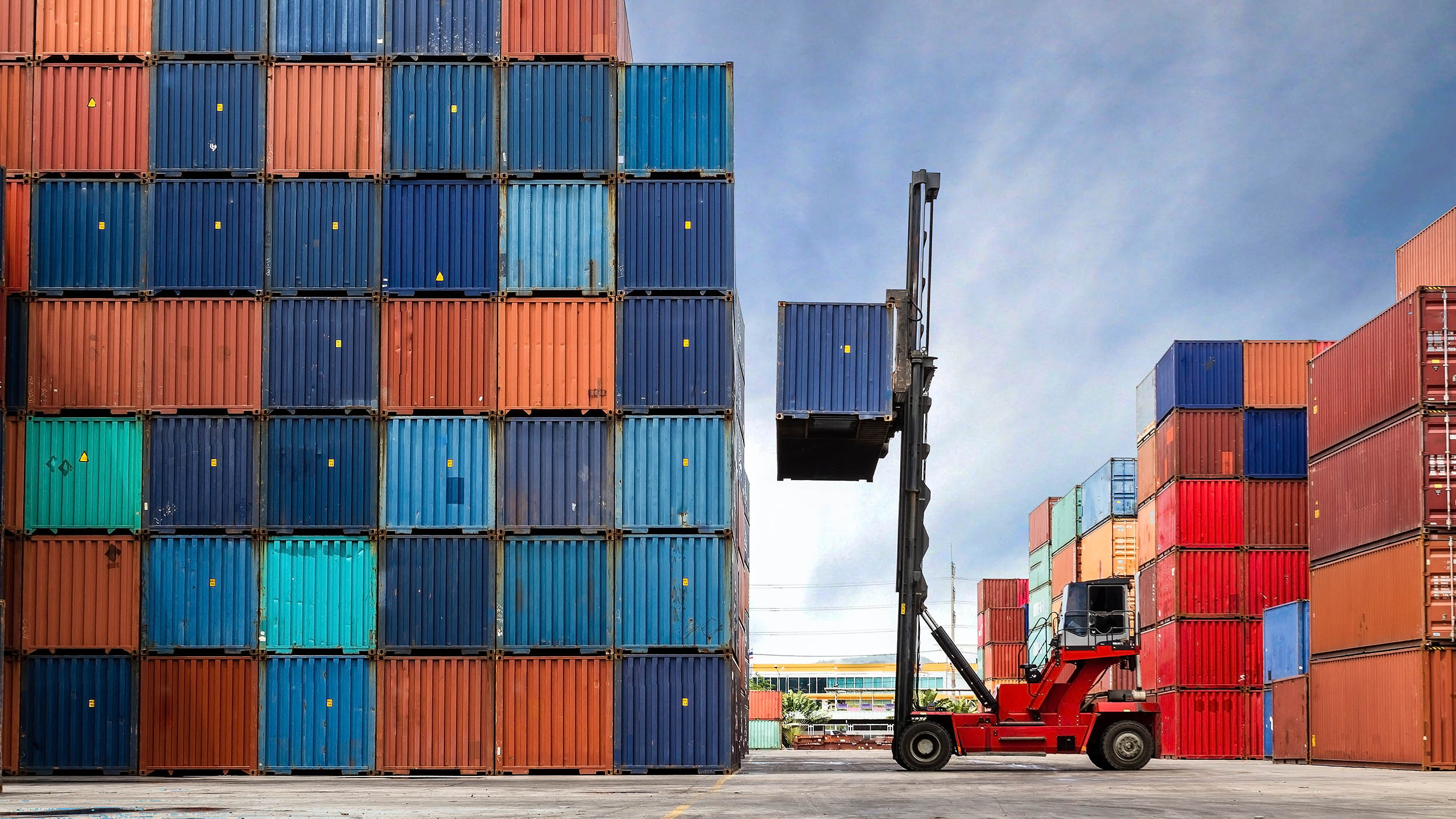 Crane lifting up container in a shipping yard.