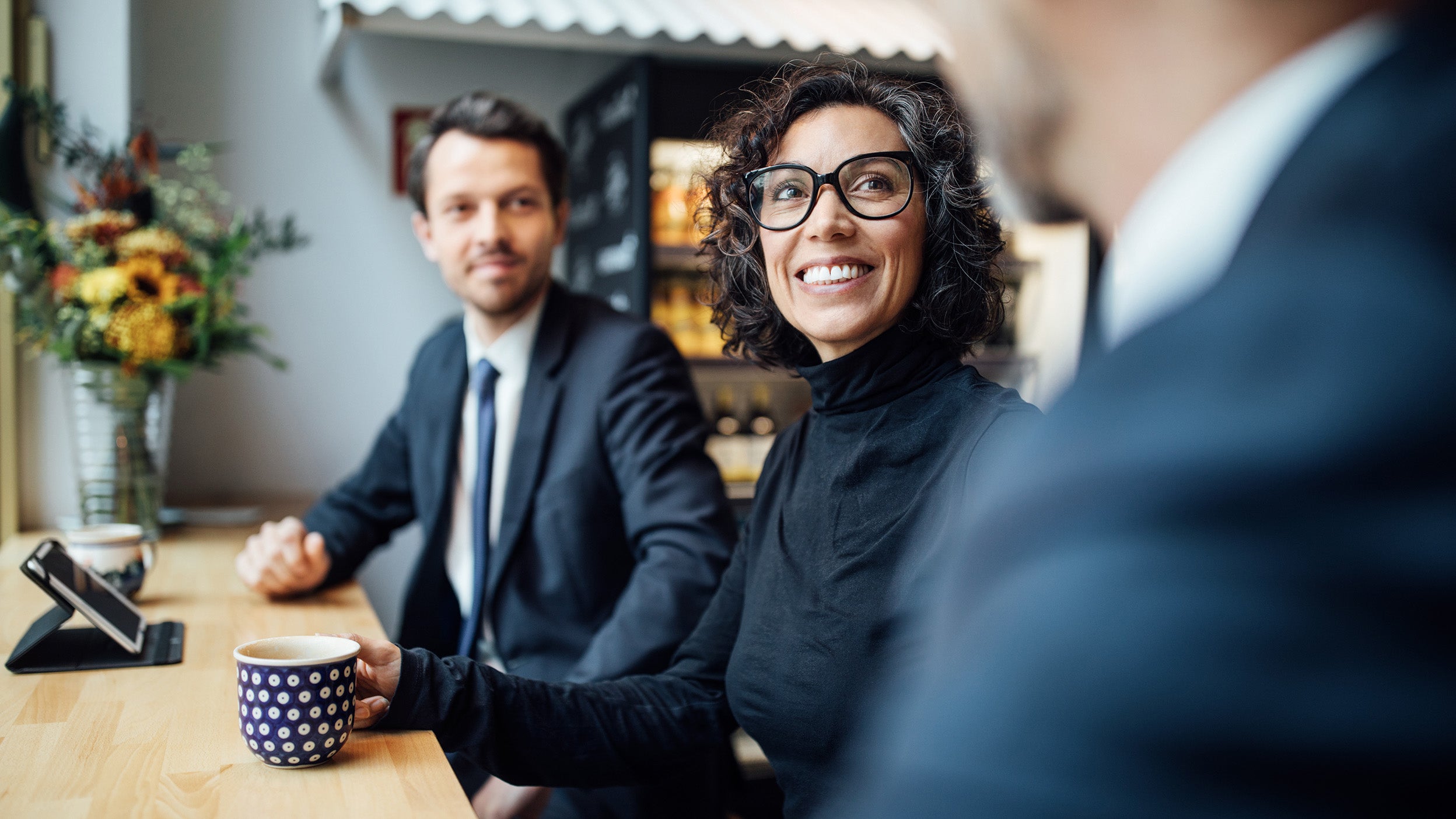 Three people dressed in business casual wear having a conversation.