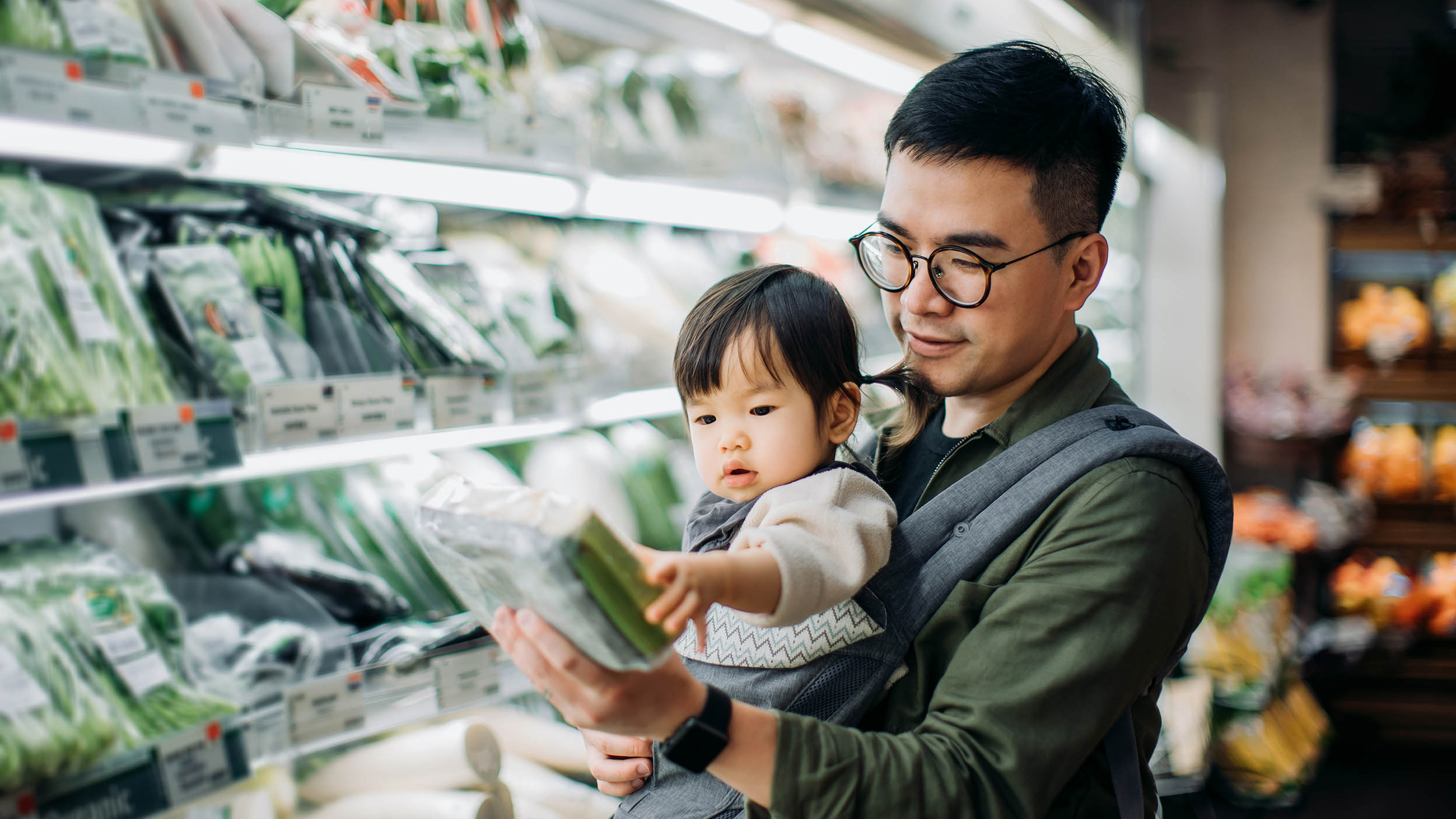 Un jeune père asiatique et sa jolie fillette font leurs courses au supermarché dans le rayon des légumes biologiques frais