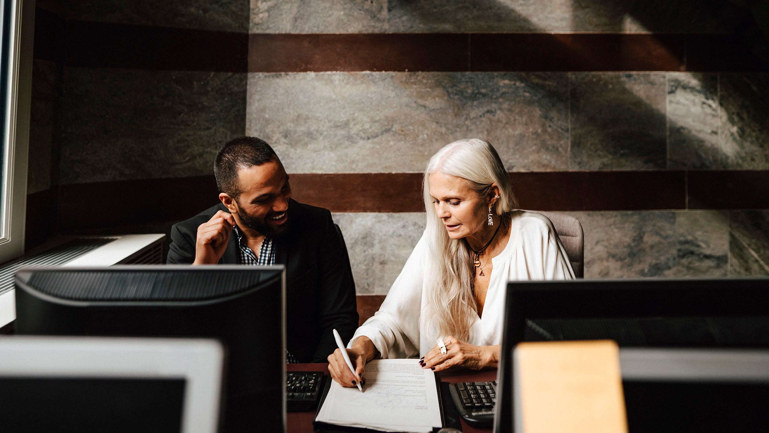 Older female financial advisor working with businessman at office