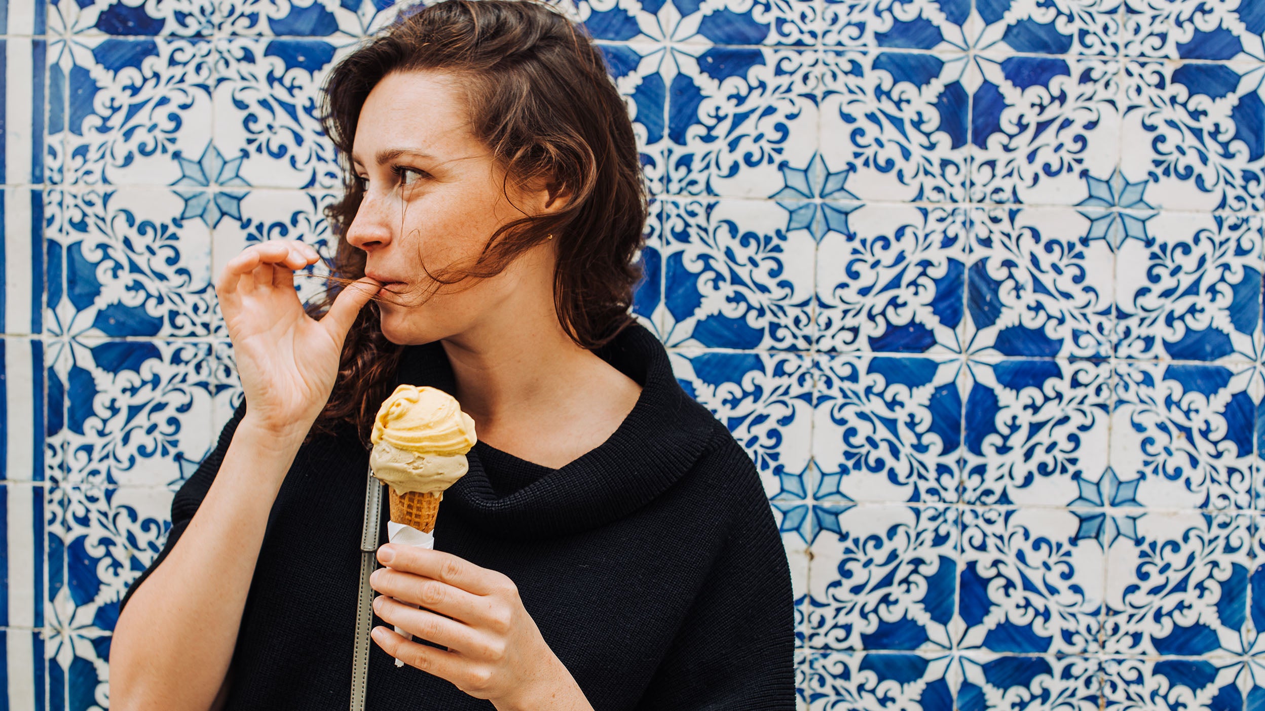 Woman holding ice cream and licking her finger